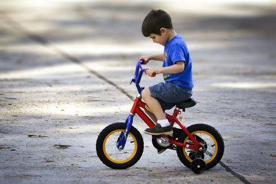 Full length side view of boy riding bicycle on street