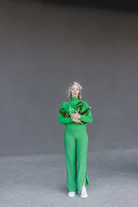 Woman with plastic bottles standing in front of gray wall