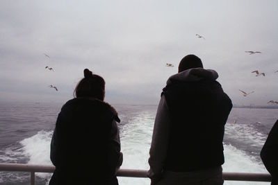 Rear view of couple overlooking calm sea