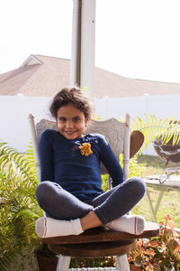 Portrait of cute smiling girl sitting on chair at home