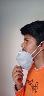 Portrait of young man holding mask against white background