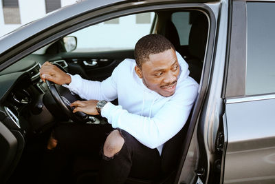 Happy african american male sitting in expensive car looking away