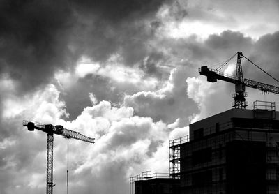 Low angle view of crane against cloudy sky