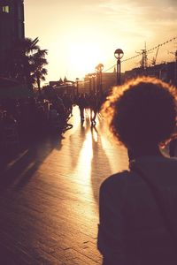 Rear view of woman in city at sunset