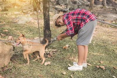 Full length portrait of boy standing with dog on field