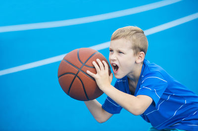 Boy with mouth open playing basketball on court