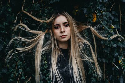 Portrait of young woman against plant