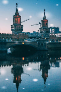 Reflection of illuminated building in river against sky