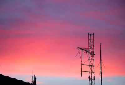 Low angle view of silhouette electricity pylon against romantic sky