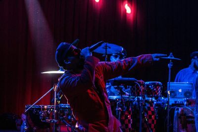 Full length of man with arms raised standing at music concert