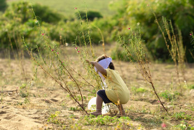 An indian child trying to catch a white balloon blown into the bushes by the wind