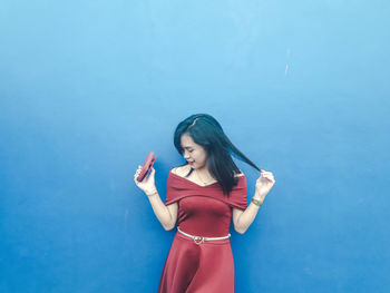 Woman in maroon dress standing against blue background
