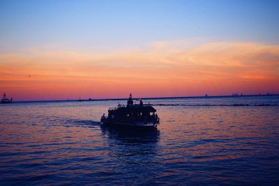 Boat sailing in sea at sunset