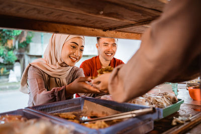 Smiling couple having food at market stall