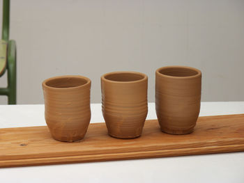 Close-up of ceramic containers on table against wall