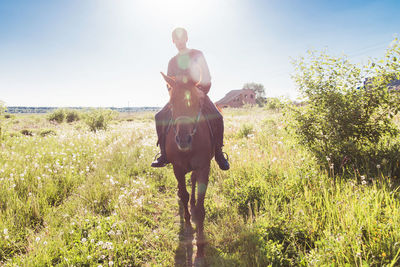 Full length of a young man riding horse on field