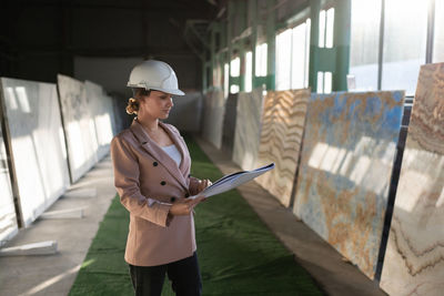 Young woman wearing hat standing against built structure