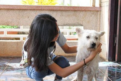 Smiling young woman holding dog at porch