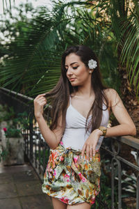 Beautiful young woman standing against railing