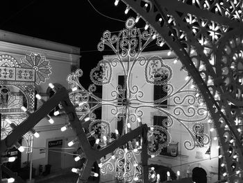 Low angle view of illuminated chandelier hanging amidst buildings