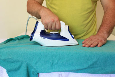 Half-length close-up of a man ironing a t-shirt at home