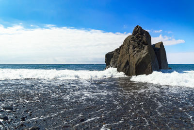 Rocks on praia formosa beach against sky