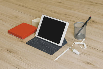 High angle view of laptop with desk organizer and cable on wooden table