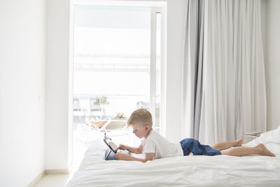 Boy on bed using digital tablet