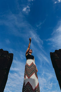 Low angle view of woman standing against sky