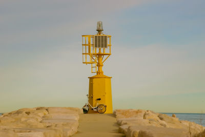 Yellow tower on beach against sky during sunset