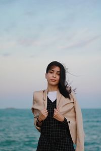 Young woman standing by sea against sky