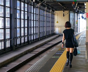 Rear view of woman in black dress walking at railroad station
