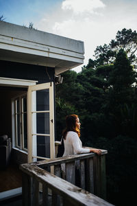 Rear view of woman sitting on seat against sky