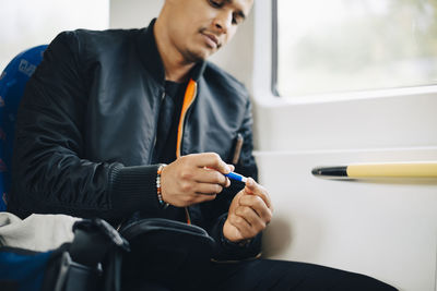 Man doing blood test while sitting in train