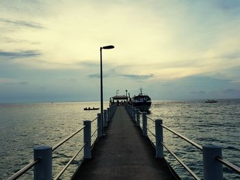 Pier on sea against cloudy sky