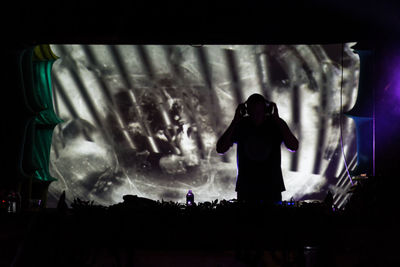 Rear view of man with arms outstretched at music concert