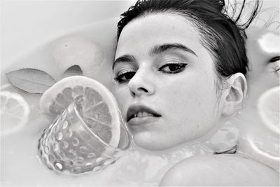 Close-up portrait of woman taking bath with fruits in bathtub