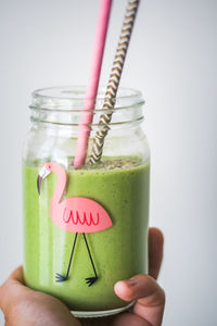 Close-up of hand holding drink over white background