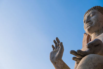 Low angle view of buddha statue against sky