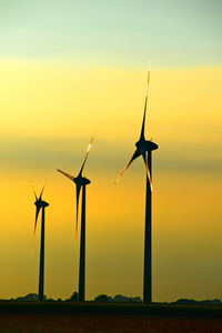 Windmills on field against sky during sunset