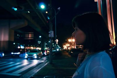 Side view of woman on city street at night