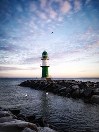 Lighthouse by sea against sky