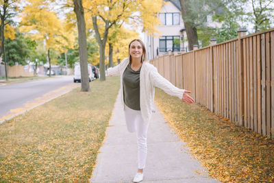 Portrait of smiling woman standing on footpath