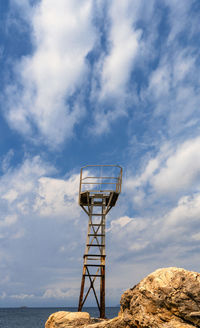 Observation point at beach against cloudy sky during sunny day