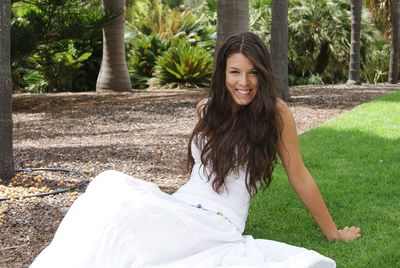 Portrait of young woman wearing white dress while relaxing on grass at park