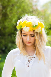 Woman wearing flowers against trees