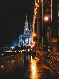 People walking on illuminated bridge at night