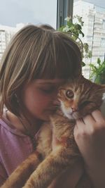 Portrait of young woman with cat at home