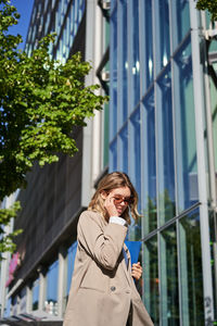 Portrait of young woman standing against building