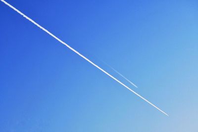 Low angle view of vapor trail against clear blue sky